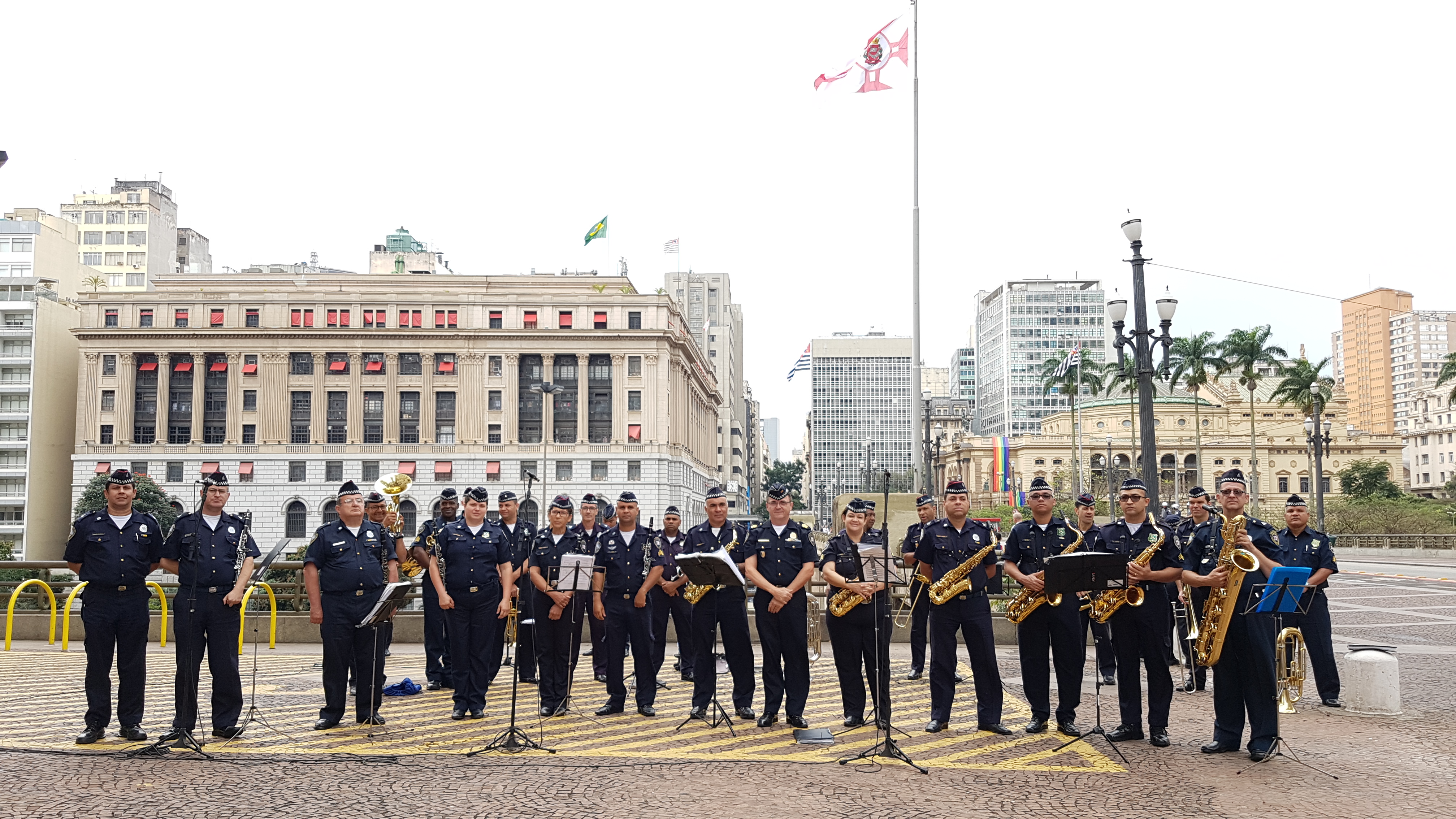 Foto colorida mostra  a banda da Guarda Municipal Metropolitana. Ao undo, o Shopping Light.